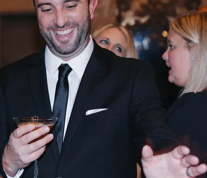 A guest with a cocktail poured by a Spark bartender
