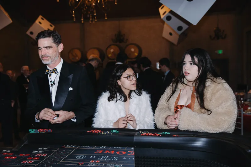 Guests at a Spark craps table under hanging dice at a gala