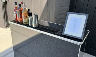 The Spark portable bar set up outdoors with bottles and a menu card