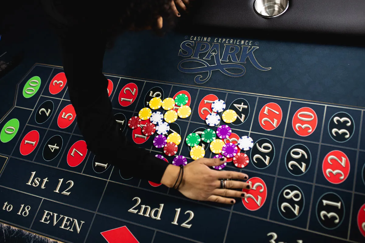 A Spark dealer running the roulette wheel at an evening casino night party