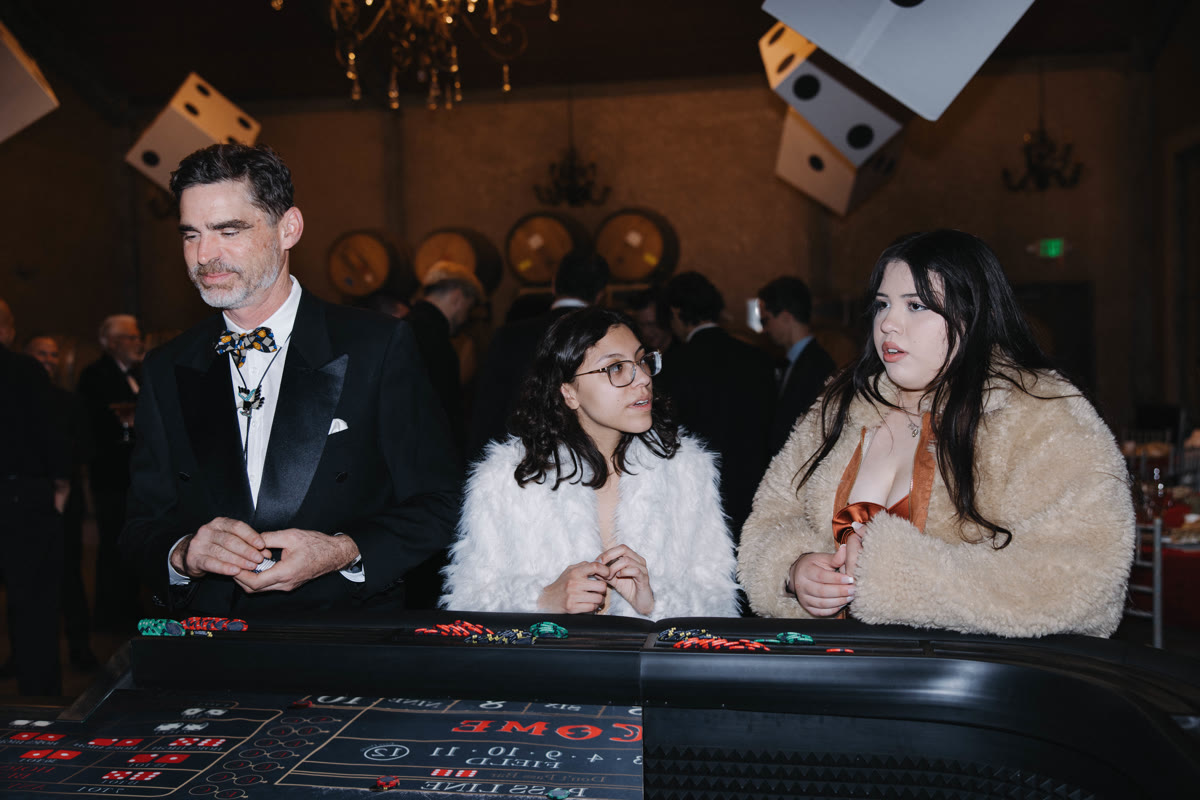 Guests at a Spark craps table under hanging dice at a gala