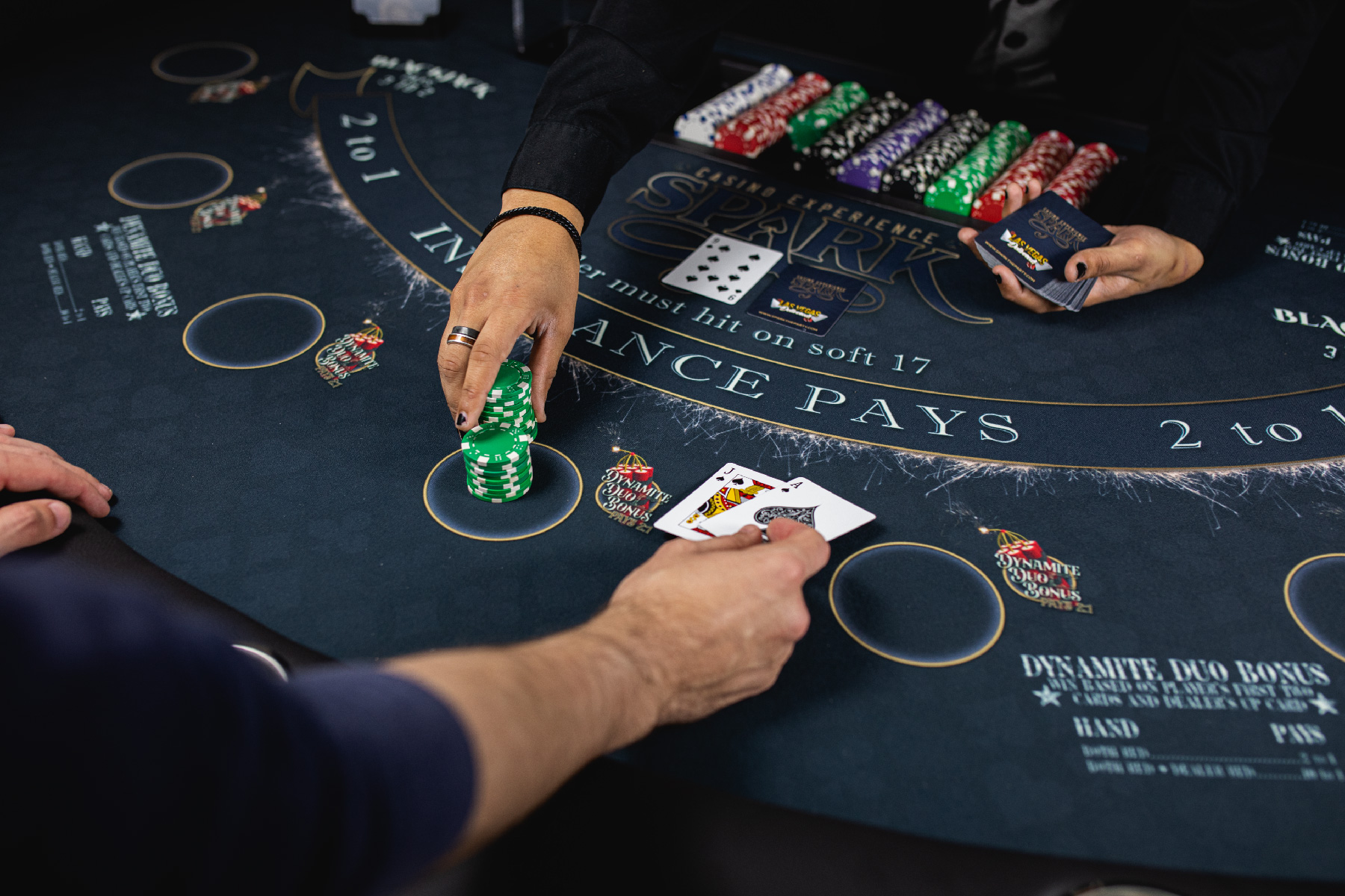 Guests learning blackjack from a dealer at a Spark casino table